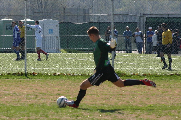 young male in a green shirt kicking a soccer ball
