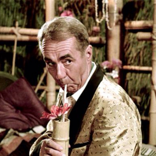 a man in an oriental suit sipping from a straw