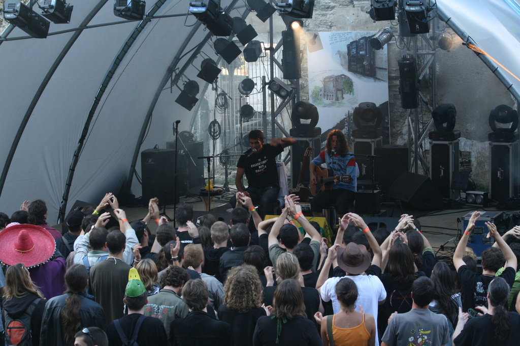 many people are gathered on a stage to record a band