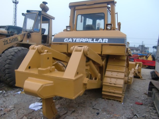 two tractors sitting in gravel, one with the front end showing