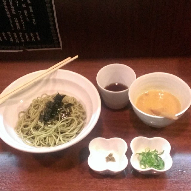 three bowls of noodles, chopsticks, and sauces sit on the table