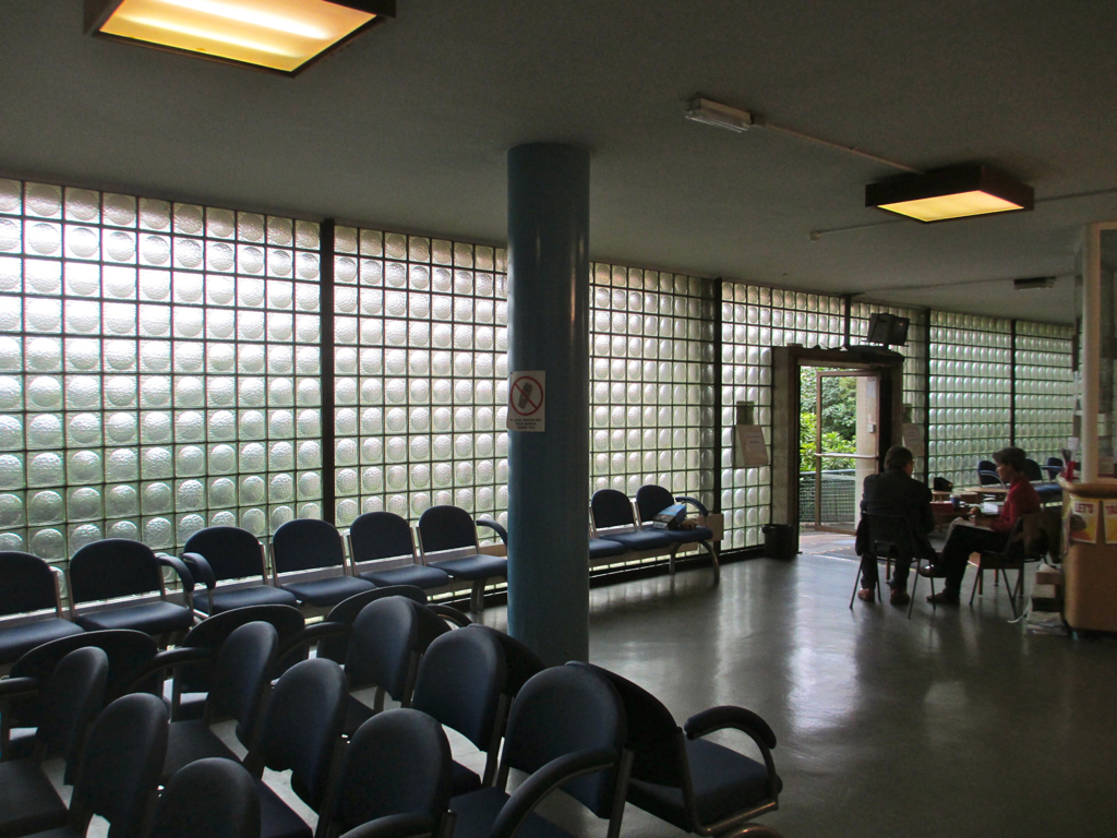 many chairs sit in a long room with a wall covered by windows