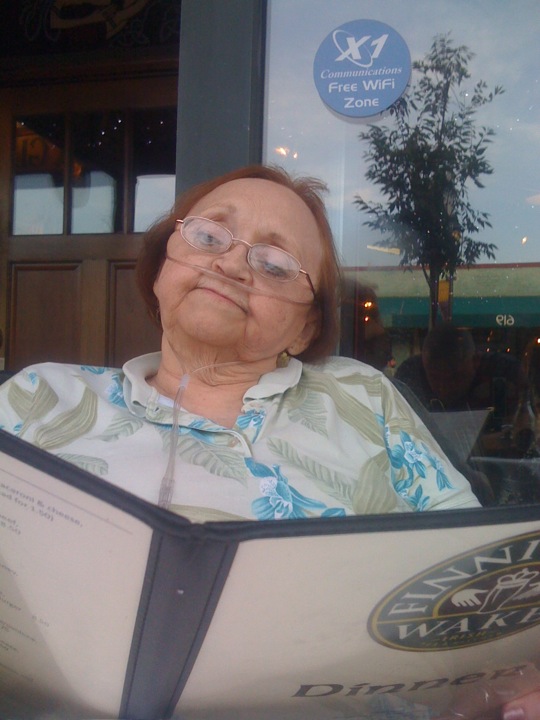 an old woman in glasses is holding a book outside of the window