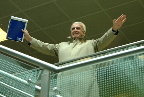 a man standing on the balcony holds up his tablet