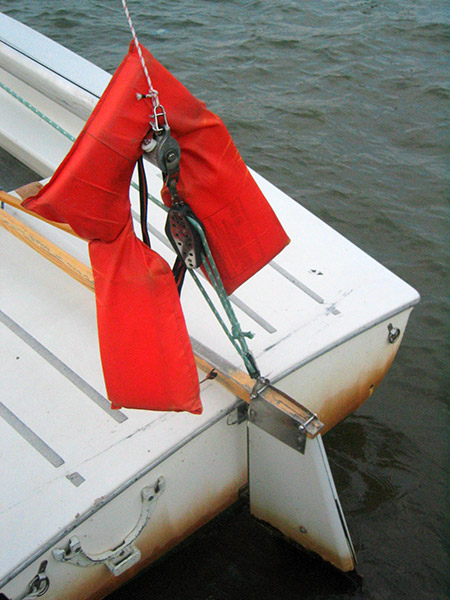 boat tied to side of dock with large red sail