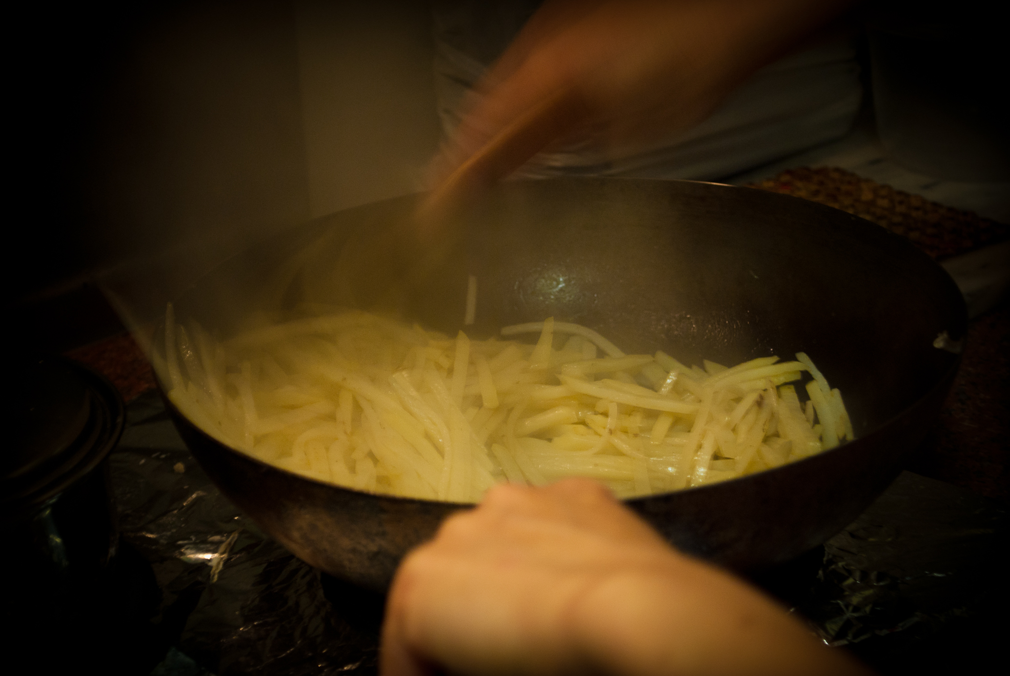 a person frying a pan filled with pasta