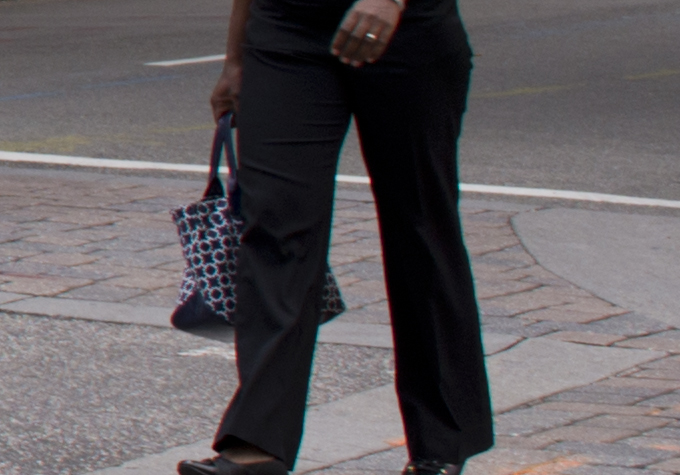 a woman in a suit holding a handbag on the sidewalk