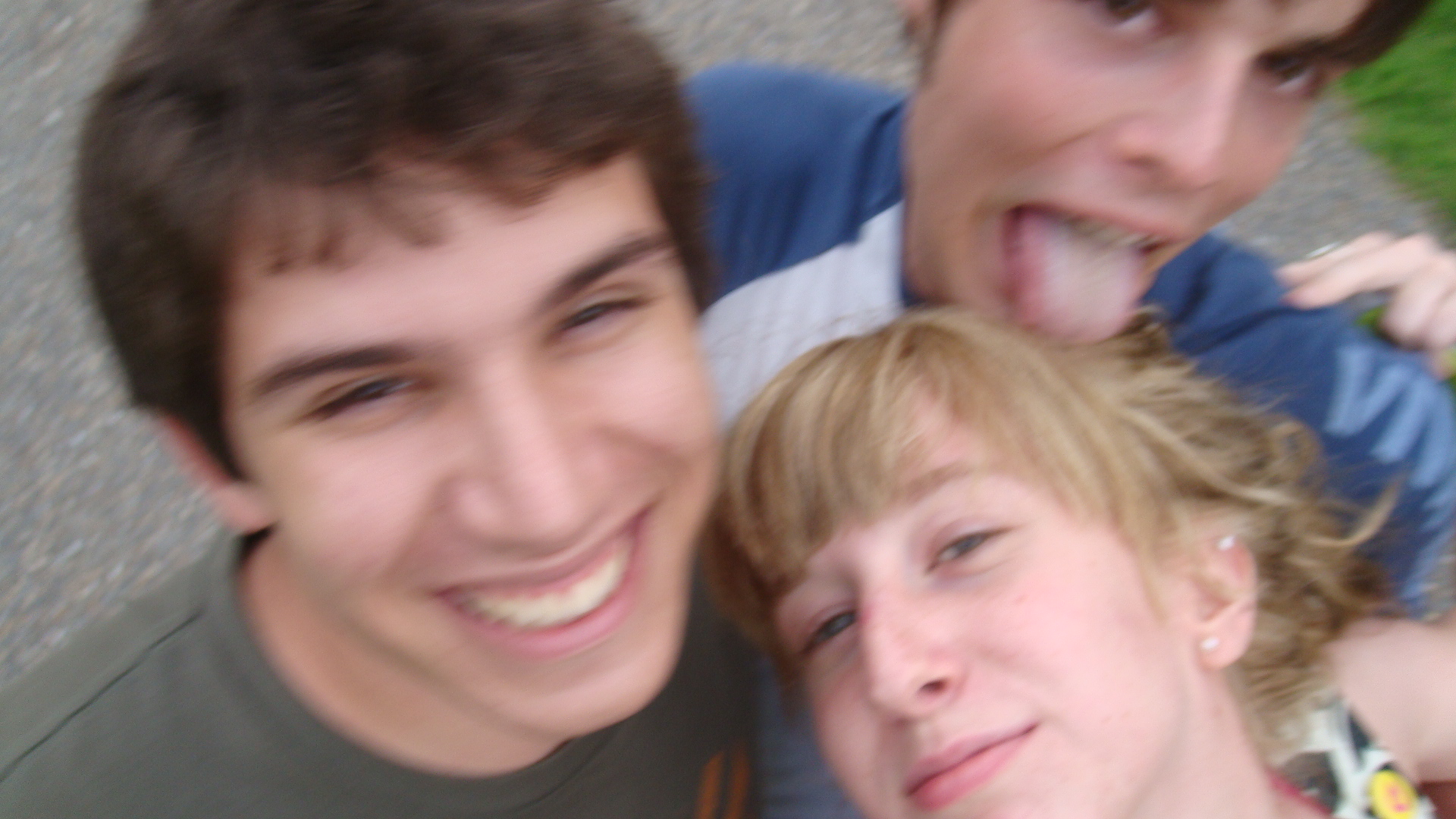 three young men, one smiling and the other making funny faces