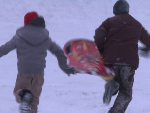 a couple of guys in the snow carrying skateboards