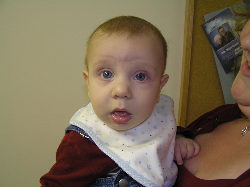 a woman holding a small child who is wearing a bib