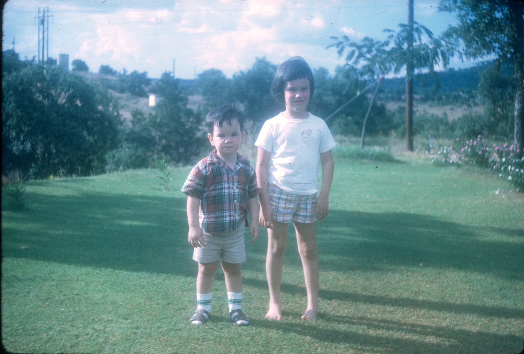 two little boys standing next to each other in the grass