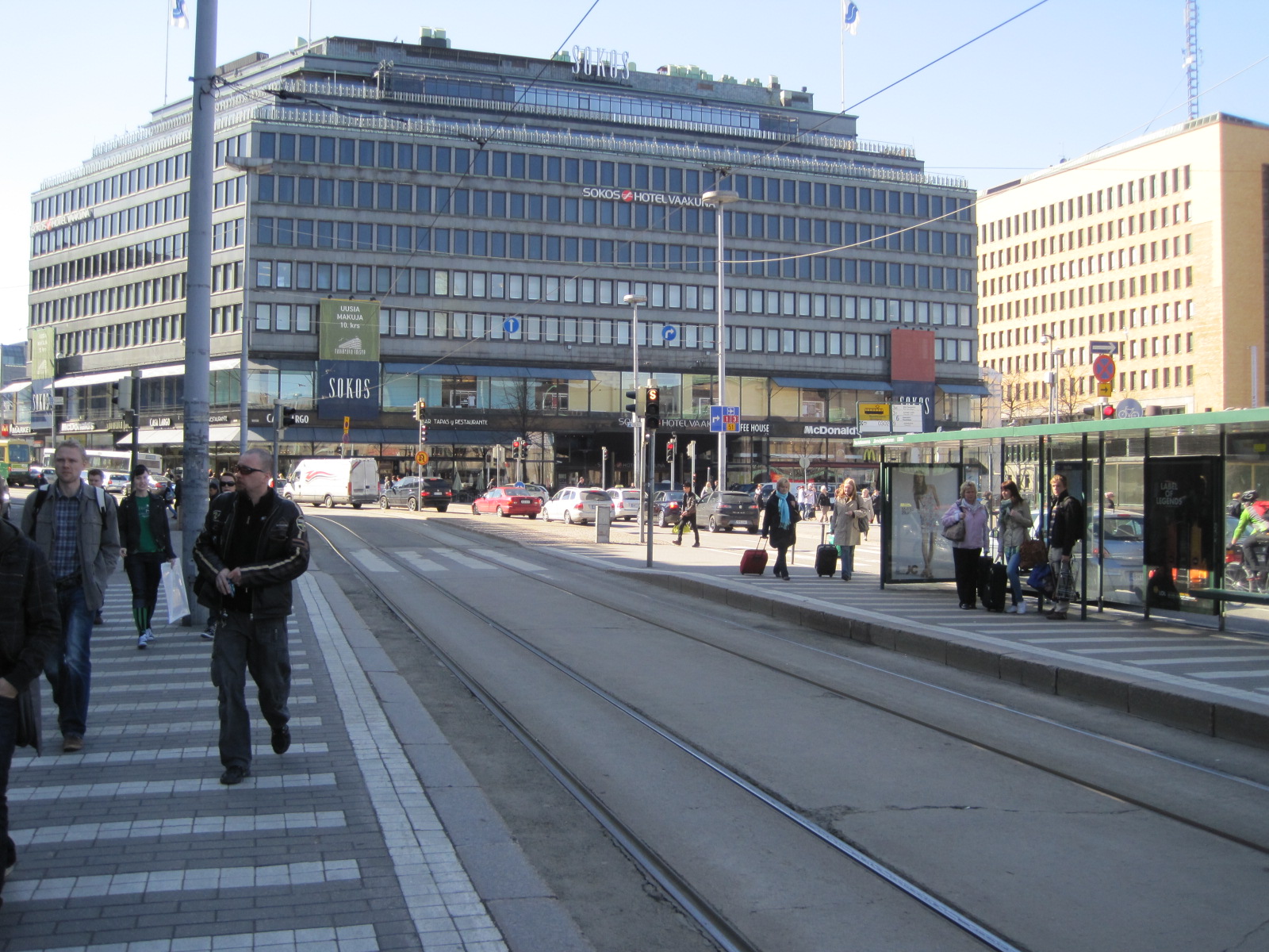 people walk through an empty street near a busy train track