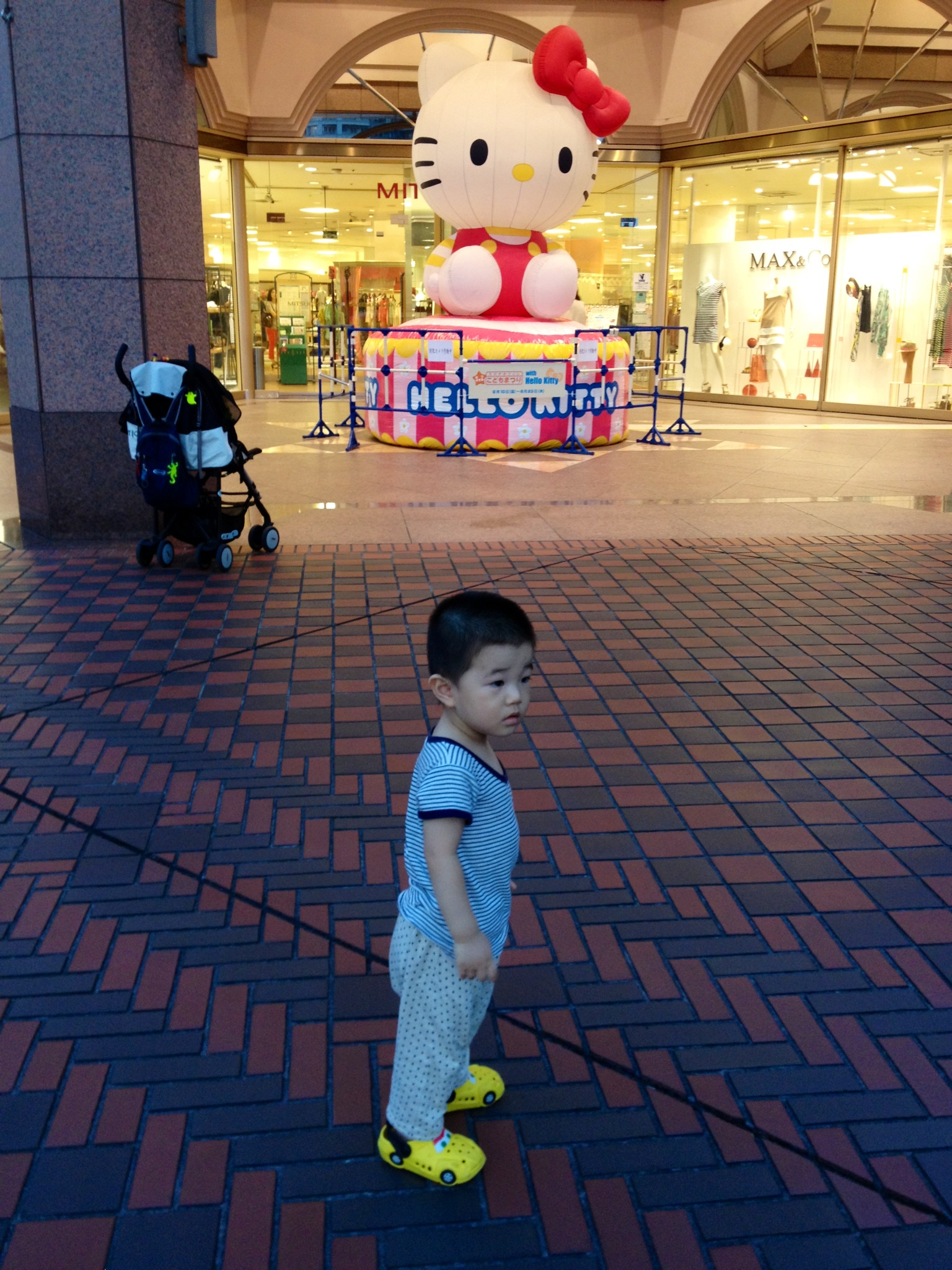 the small boy is standing in front of the hello kitty store