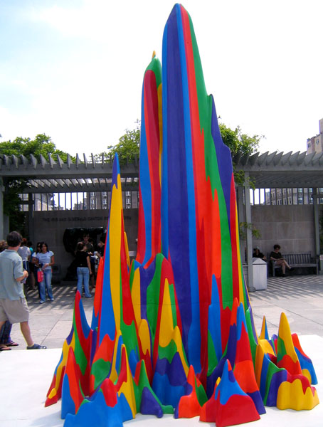 a group of people standing around a building made out of plastic bottles