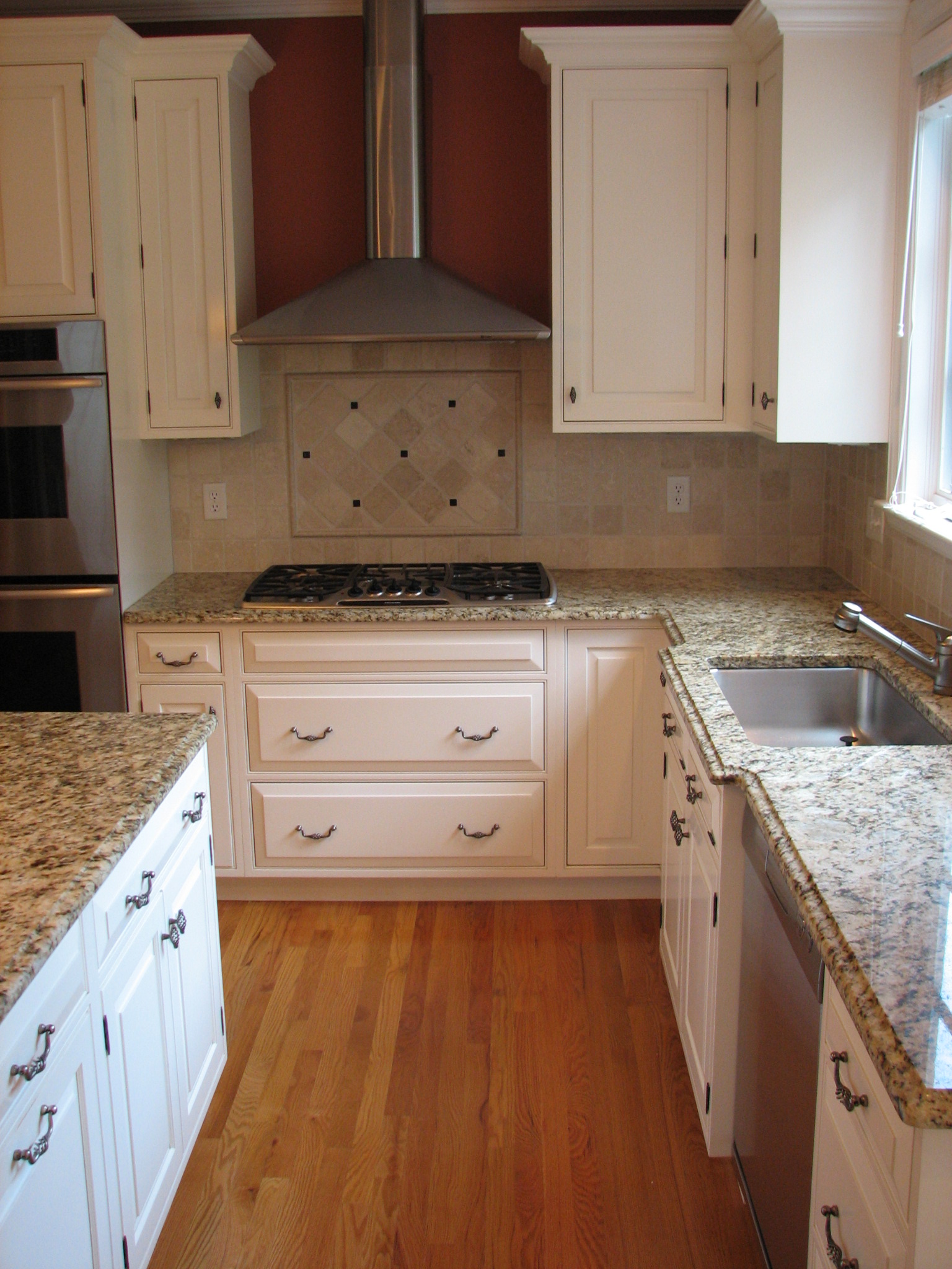 an empty kitchen with white cabinets and marble counters