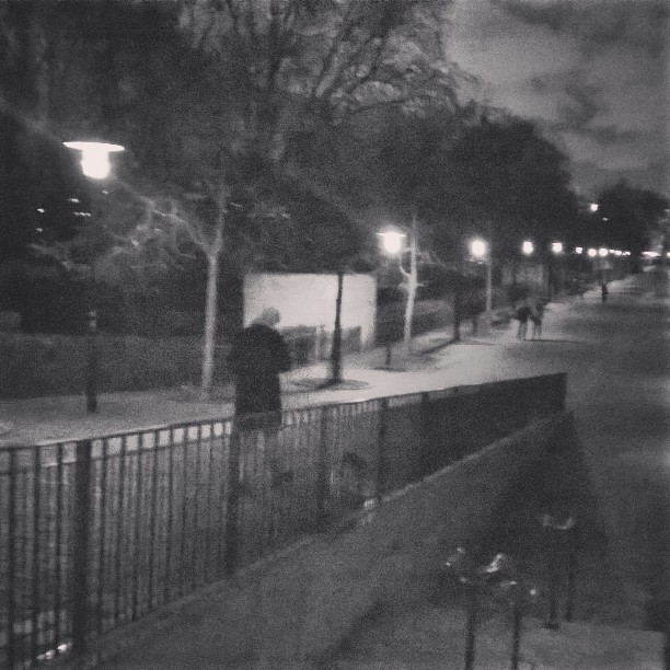 black and white pograph of people walking by sidewalk at night