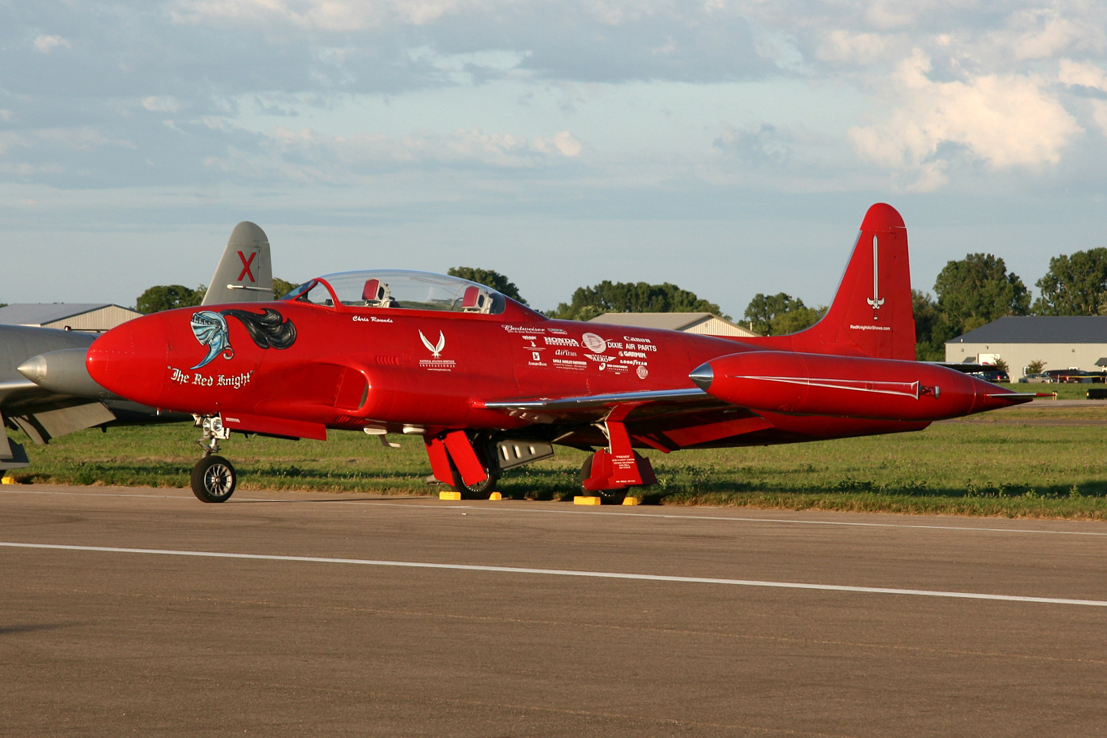 a red and silver fighter plane parked on the tarmac