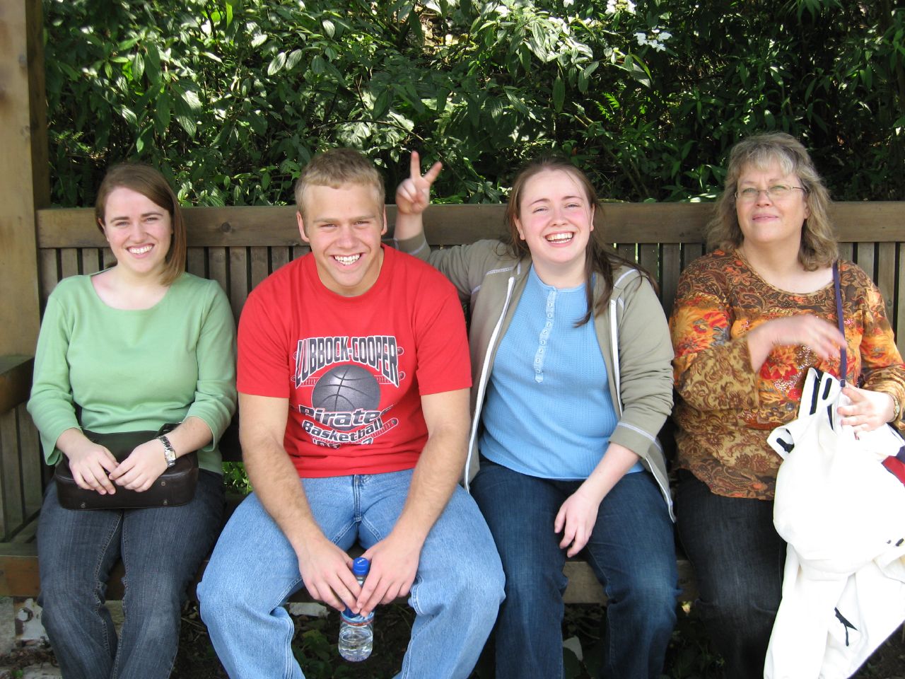 three people sitting on a bench in front of trees