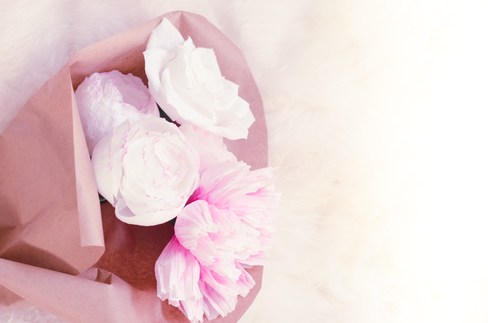 two large white and pink flowers on top of a piece of paper