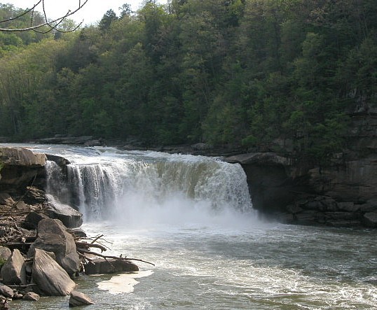 a large waterfall near rocks and trees