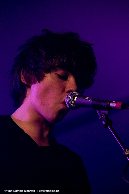 a male singer in a black shirt singing into a microphone