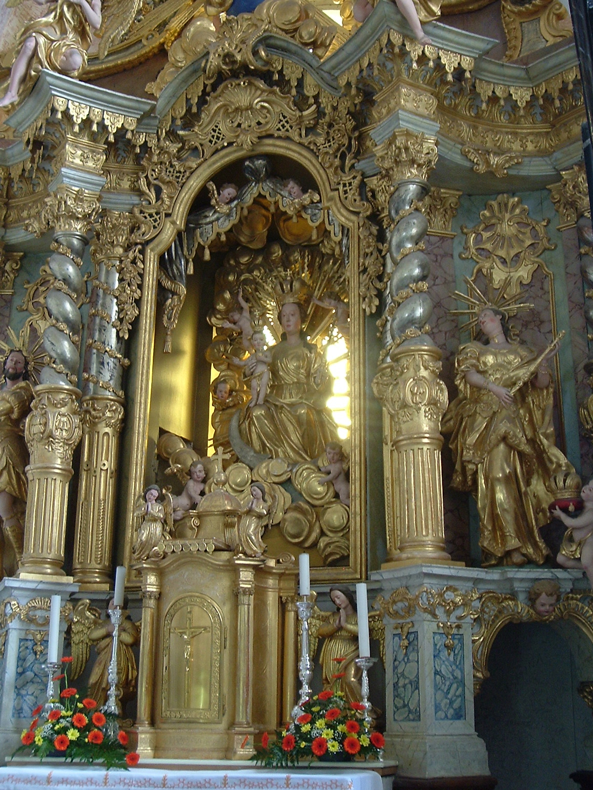 a church altar with golden statues and windows