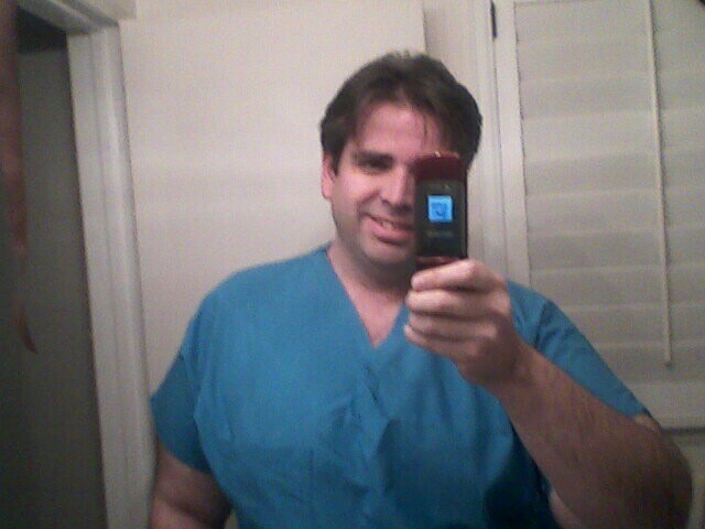 man in scrubs taking a selfie with cell phone
