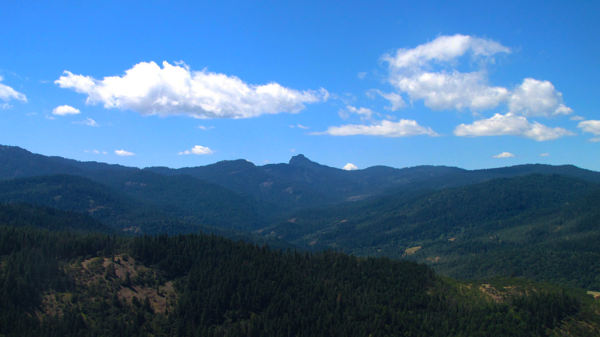 a distant view of a mountain range with trees on both sides