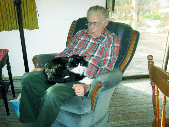 a man sitting in a chair holding a black and white cat