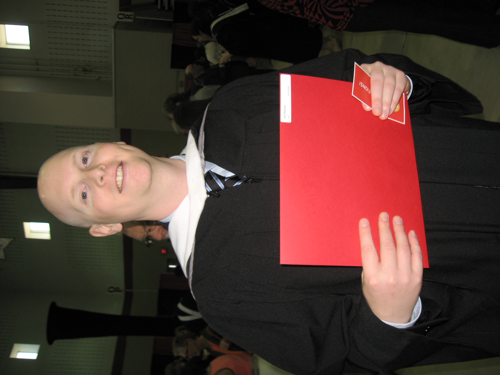 a man wearing a tie and gown stands inside a building