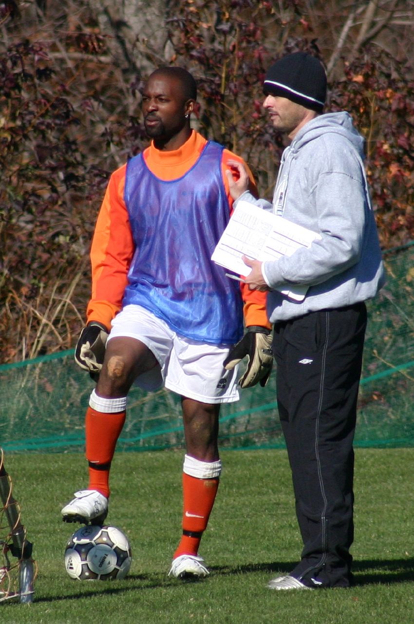 a person is standing near a soccer player with his leg on the ball