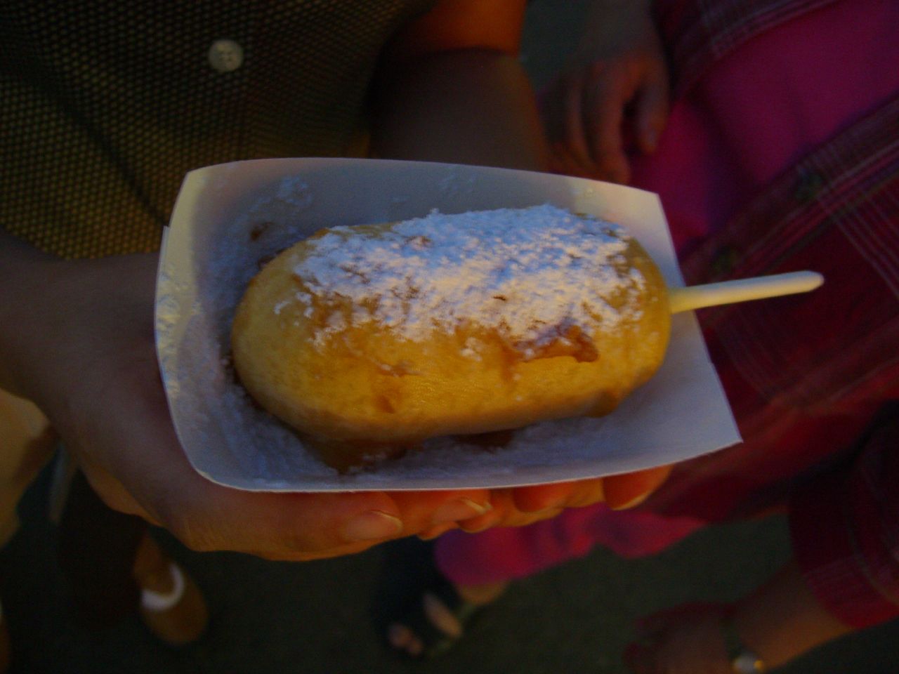 a white paper container holds a half eaten pastry