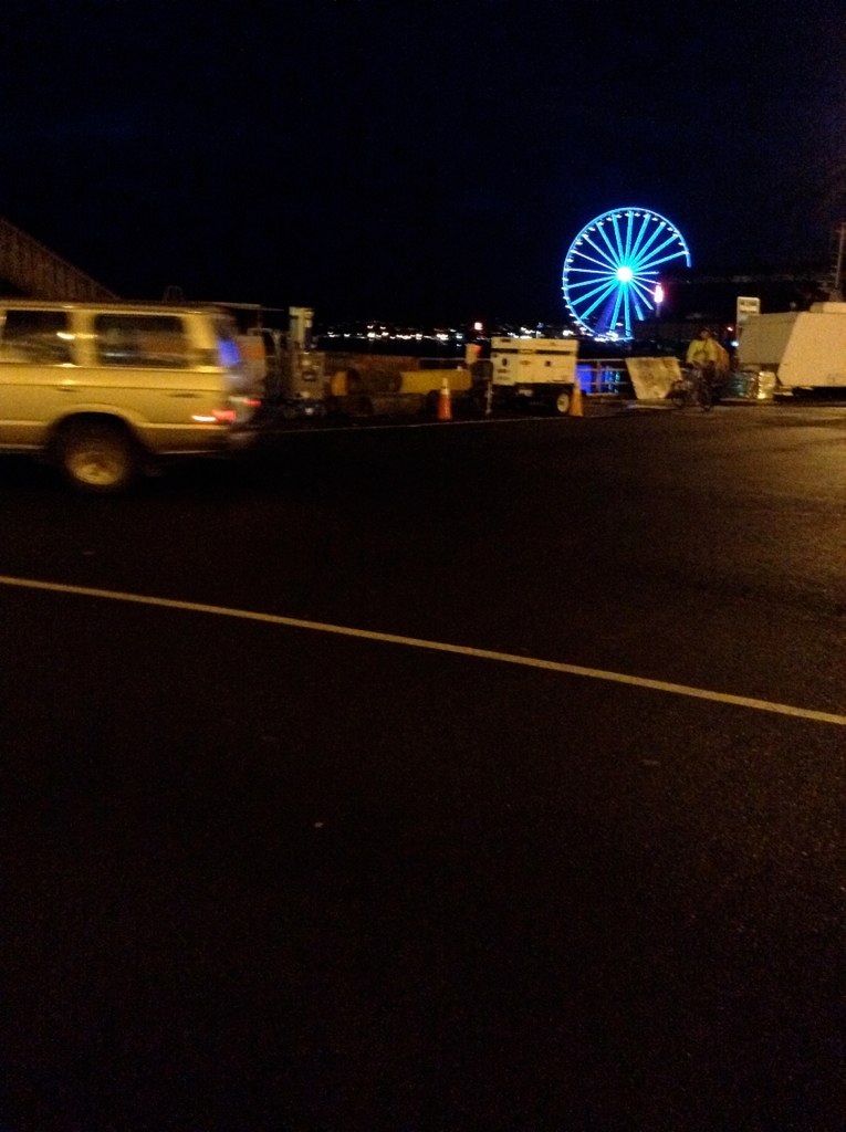 the truck is driving down the street near the large ferris wheel