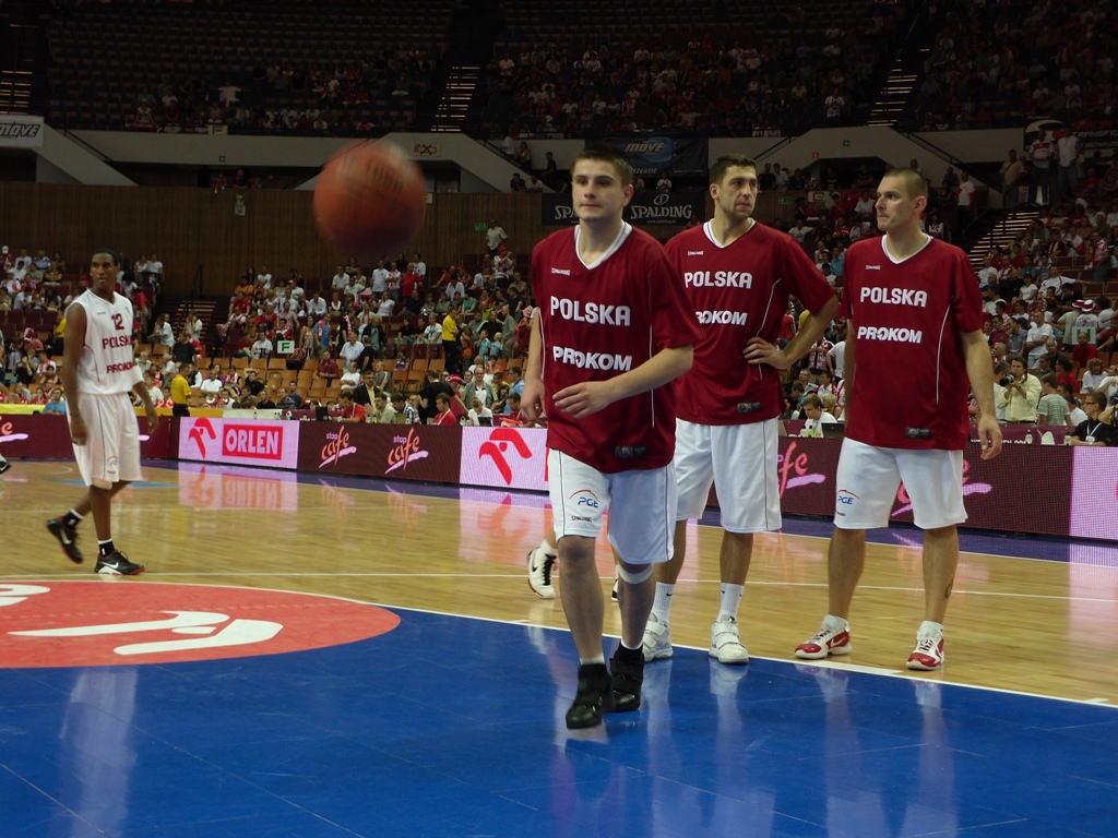 basketball players stand on a court as one player passes the ball in front of them