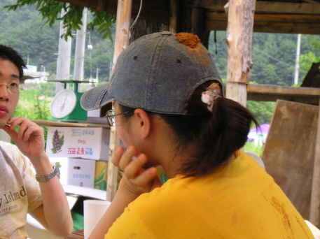 a man in a baseball cap is talking to an asian woman