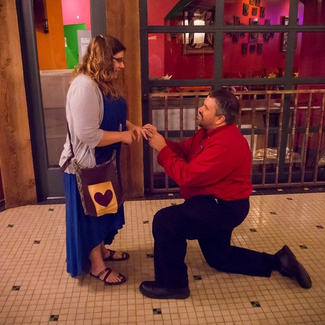 man kneeling down to his girlfriend while they are looking at each other
