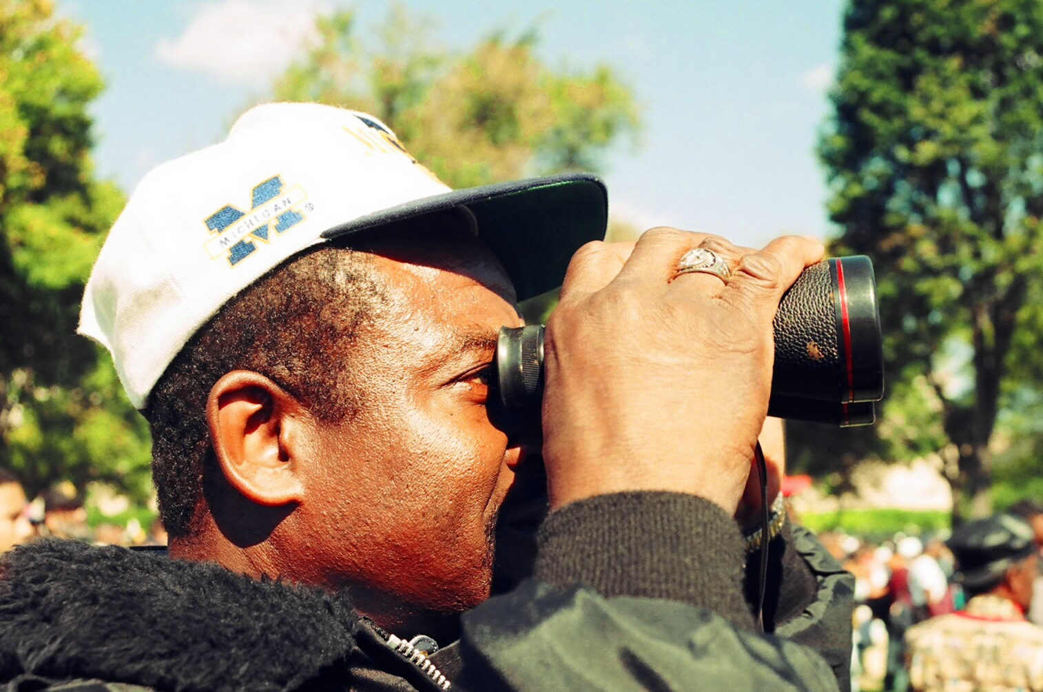 a man in a cap looks through the camera with his finger on a lens