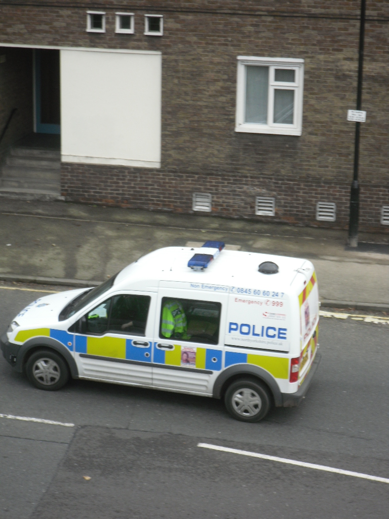 an police vehicle driving down a street past buildings