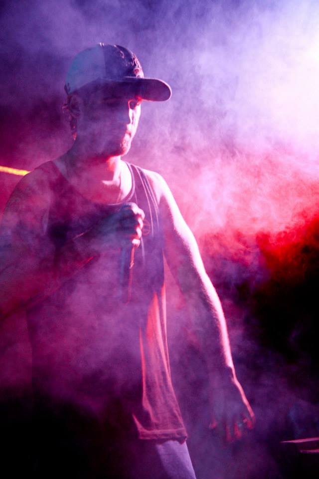 man in baseball cap walking through smoke in dark area