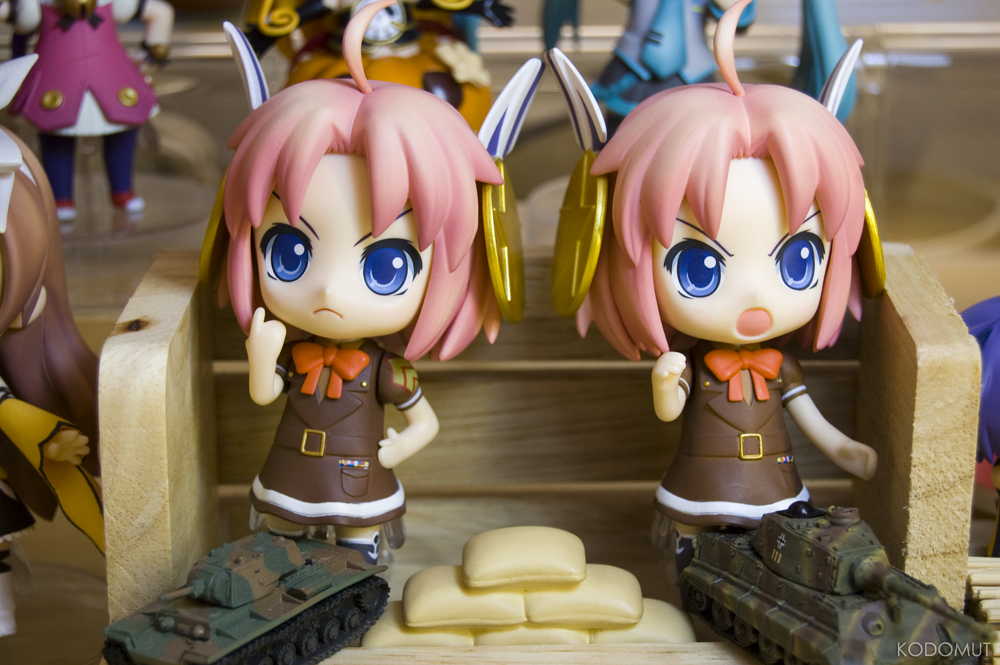 two doll figures of a girl next to an army vehicle