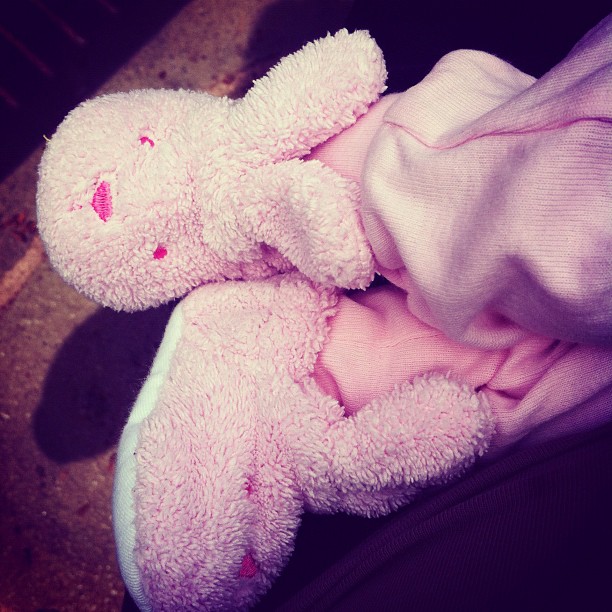 a stuffed teddy bear is laying on top of a pink and white blanket