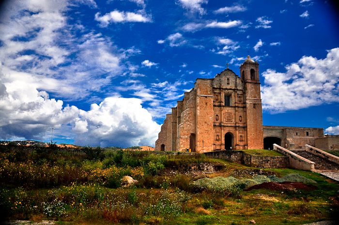 an abandoned church sits against the sky with fluffy clouds