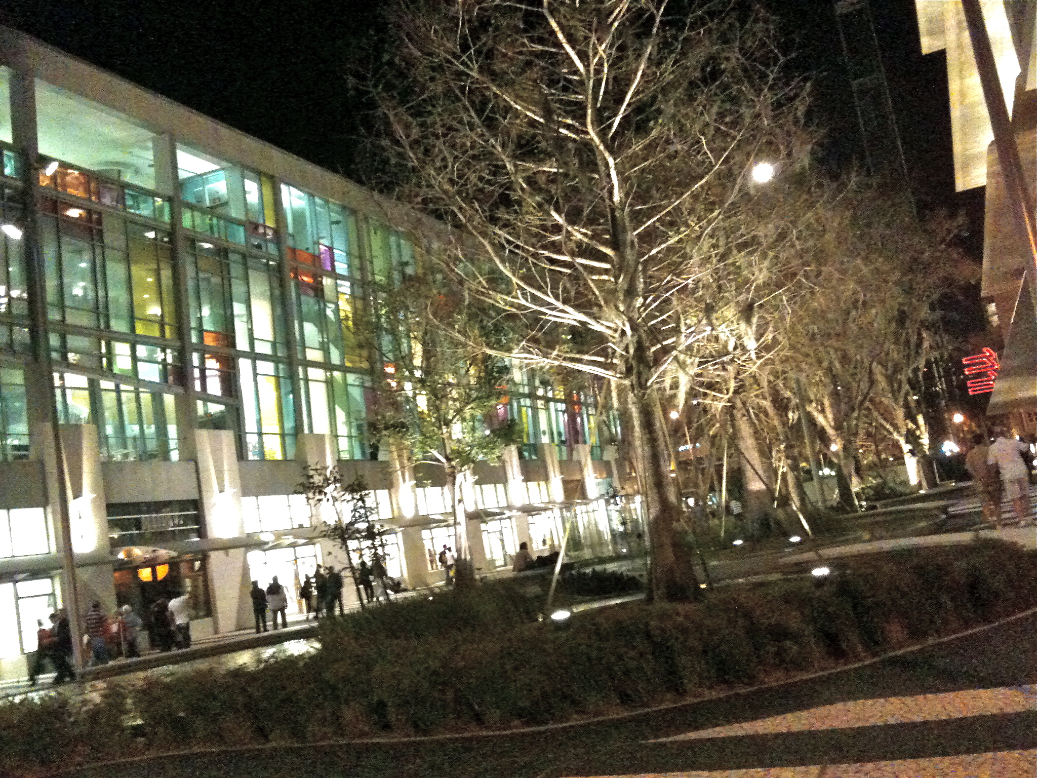 people walking on sidewalk in front of a building at night