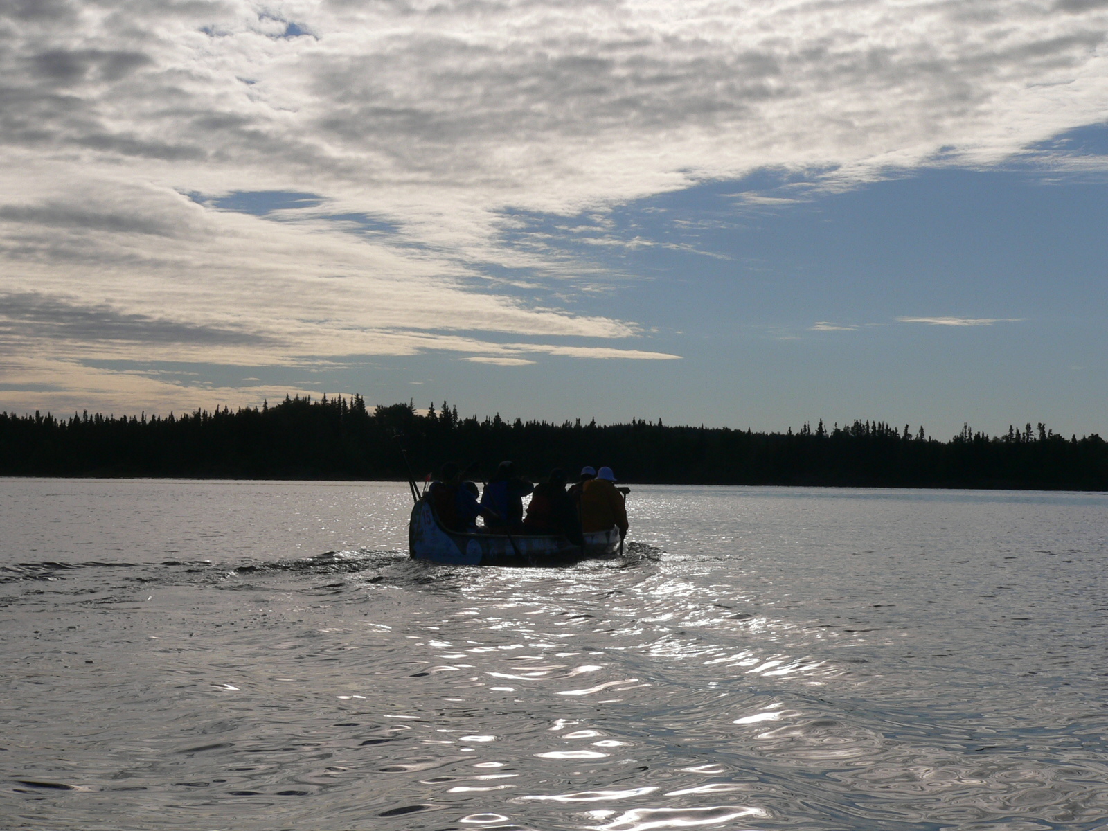 three people are in a small boat moving across the water