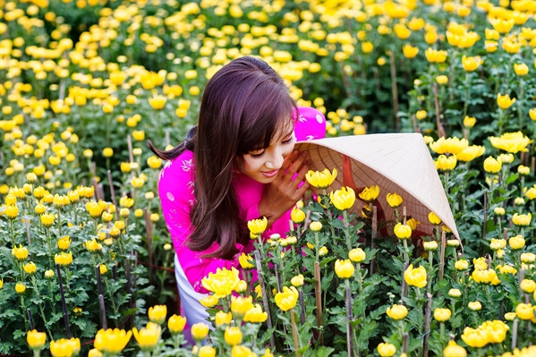 a girl kneeling in the middle of yellow flowers
