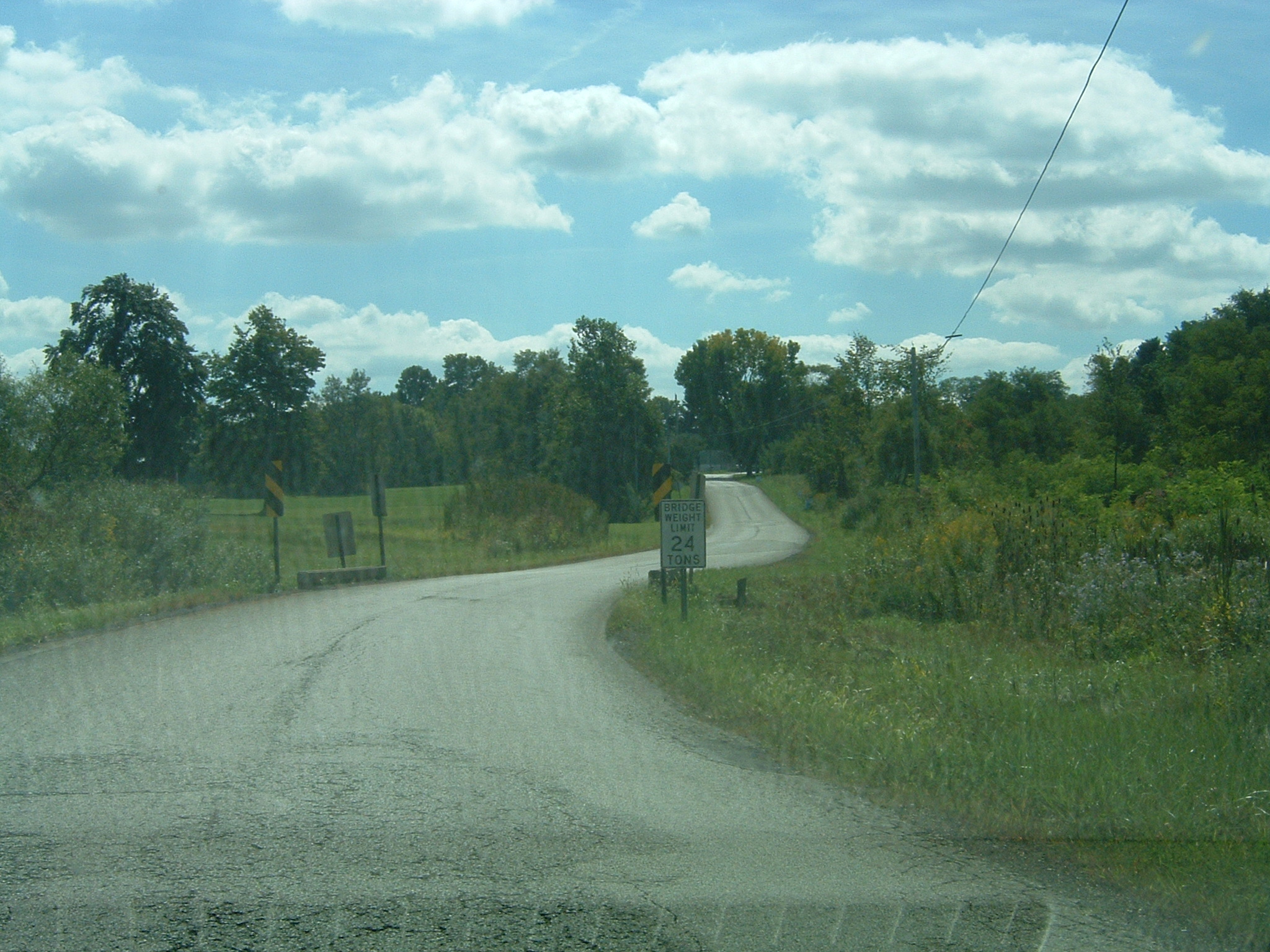 a wide paved road in a wooded area