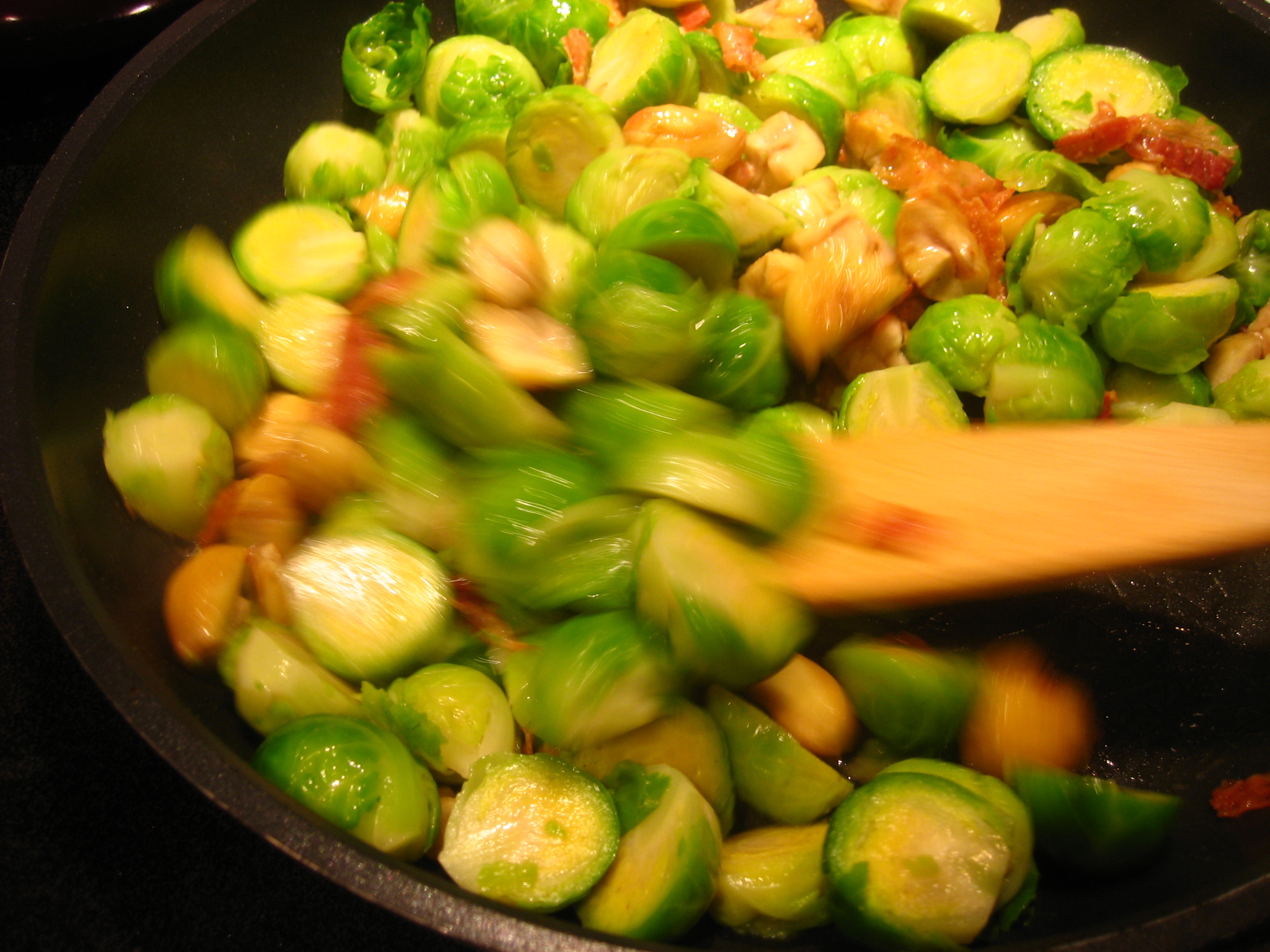 a close - up view of brussels sprouts and bacon cooking in a pan