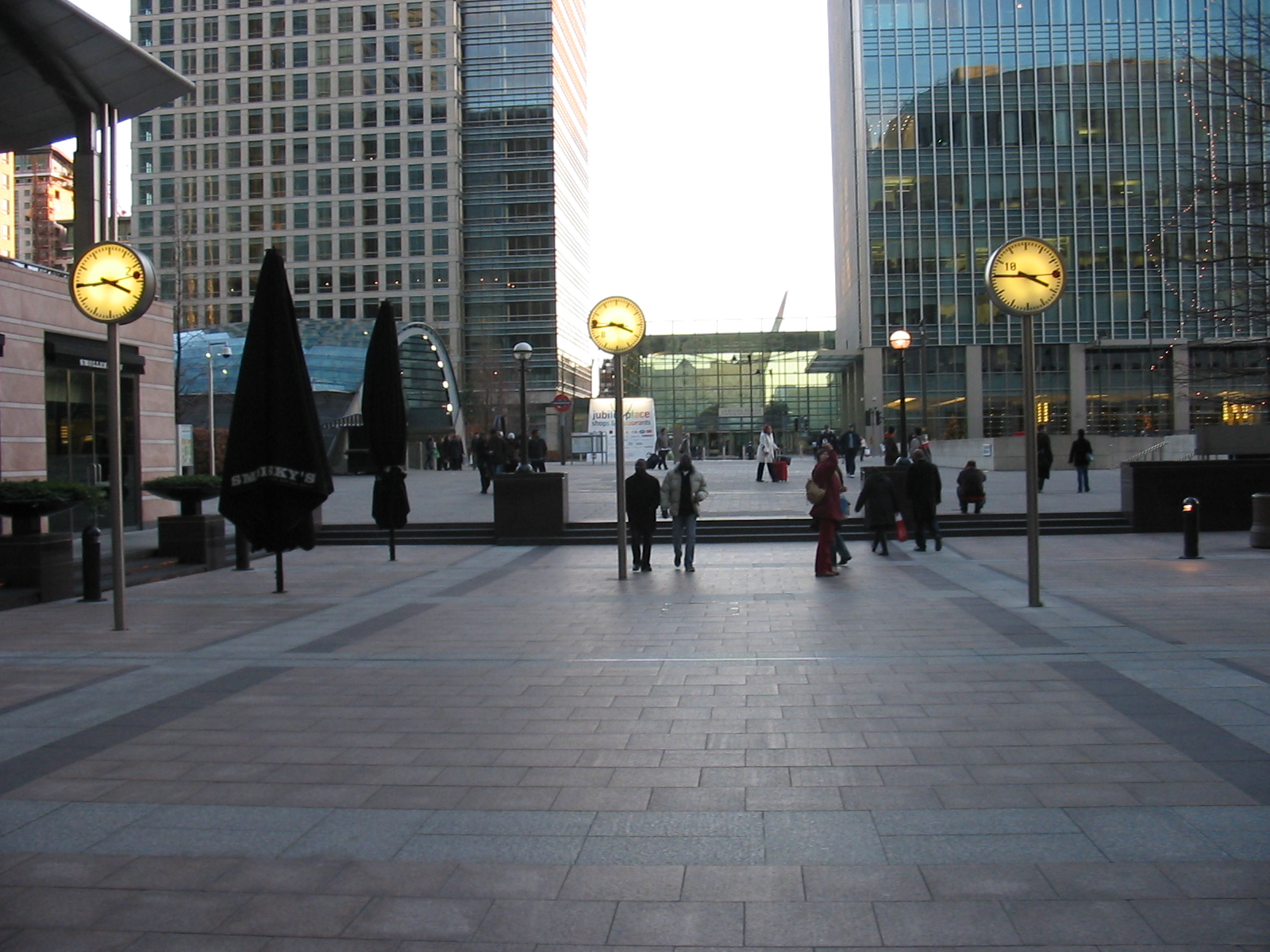 a city plaza at dusk with people walking around