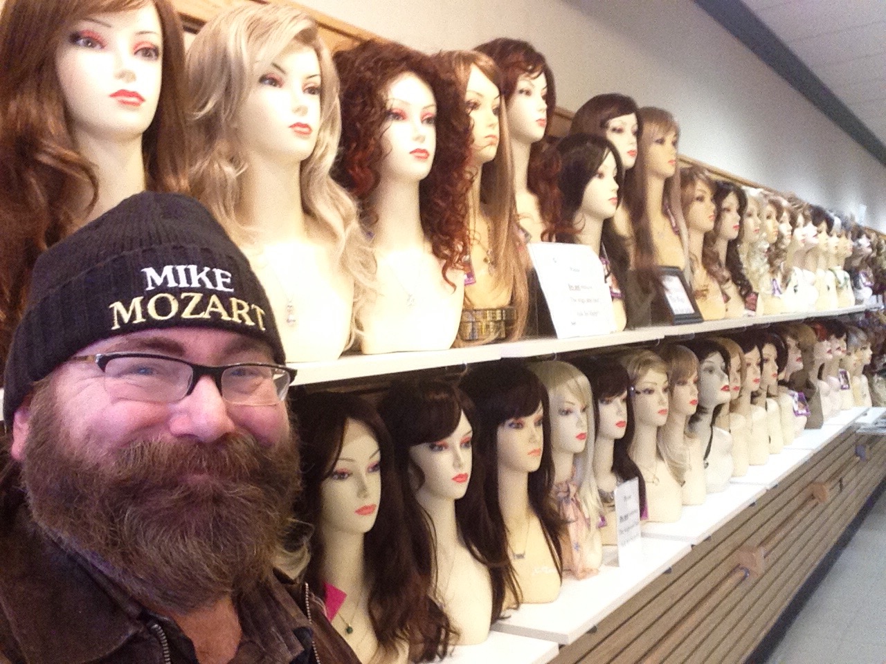 a man standing next to lots of mannequin heads