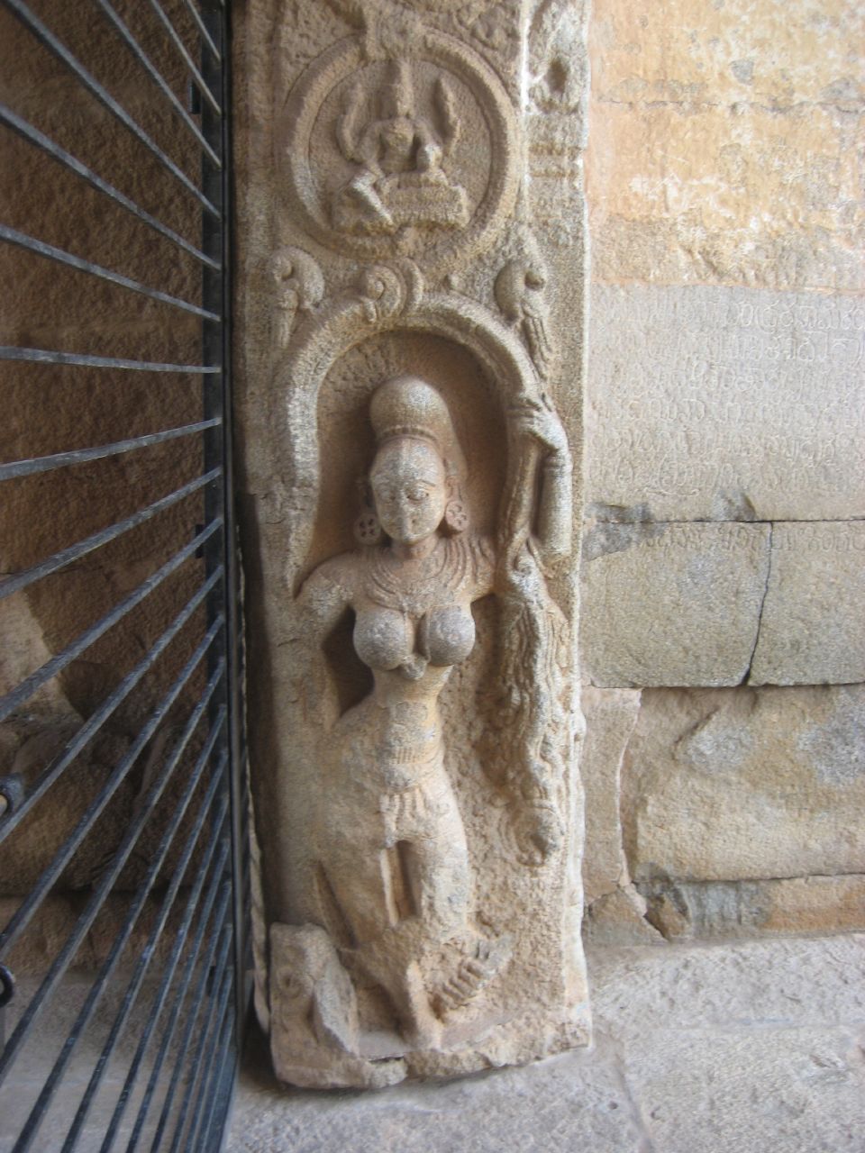 a statue with a human body and head standing next to a gate